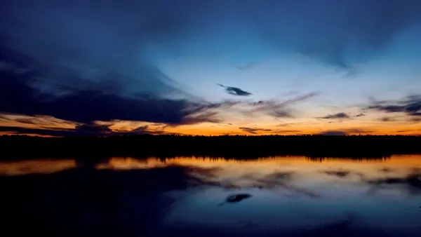 Minnesota lake at sunset with dramatic orange and blue sky reflection