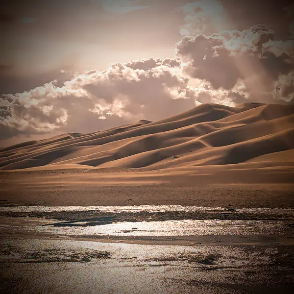 Great Sand Dunes under dramatic storm light with water reflection, Colorado