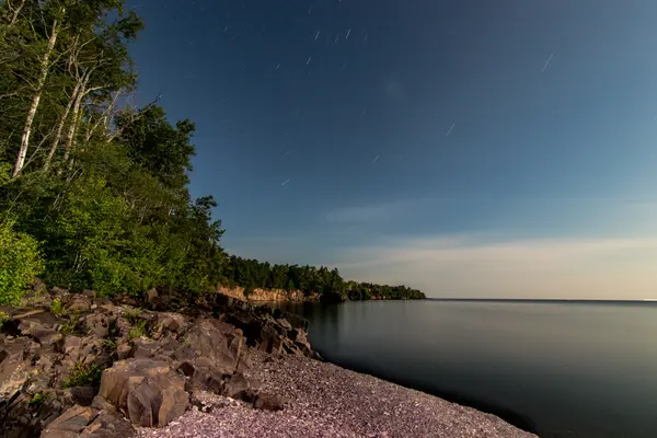Lake Superior shoreline at night with stars and rocky cliff